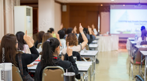 blurry image. pointing up finger with raised hands and arms of large group of people in meeting room or class room, audience voting in professional education surrounding