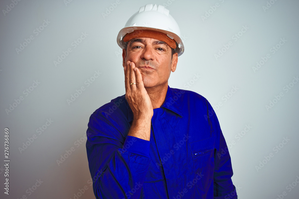 Handsome middle age worker man wearing uniform and helmet over isolated white background touching mouth with hand with painful expression because of toothache or dental illness on teeth. Dentist 