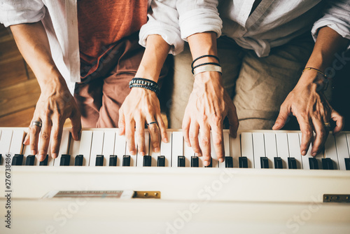 Girlfriend spend time in modern apartment. Girls learning piano playing. Top to bottom view crop hands making exercise on piano keyboard and watching tutors on smartphone screen.