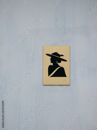 Women's gold and black restroom sign on the grey painted door