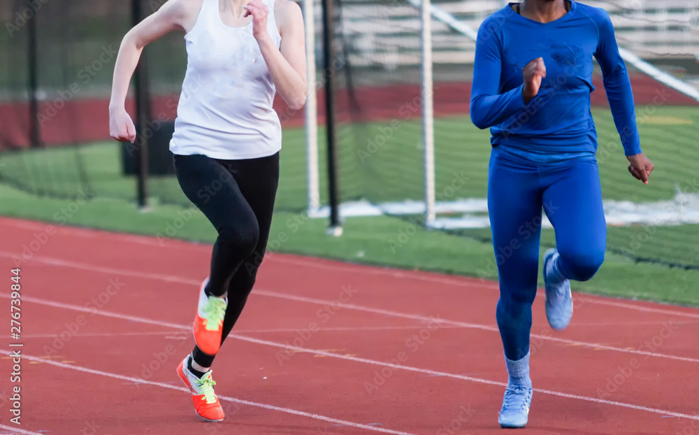 Two high school girls sprinters racing in the cold