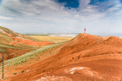 A tourist girl standing on the side of the Bolshoi Bogdo mountain on the background of the salty lake Baskunchak. photo