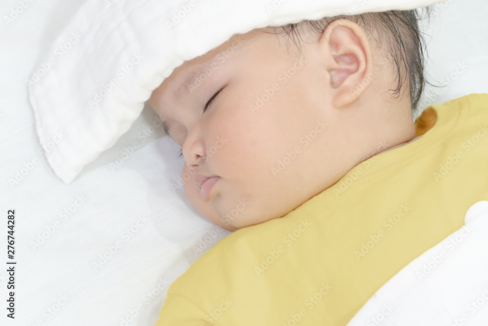 Sick baby girl sleeping with white towel at head reducing temperature Sick baby girl sleeping with white towel at head reducing temperature