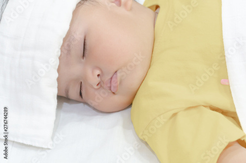 Sick baby girl sleeping with white towel at head reducing temperature