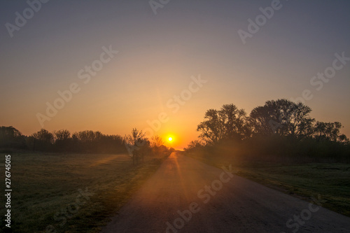 The sun rises over the old road in the countryside. © Valery
