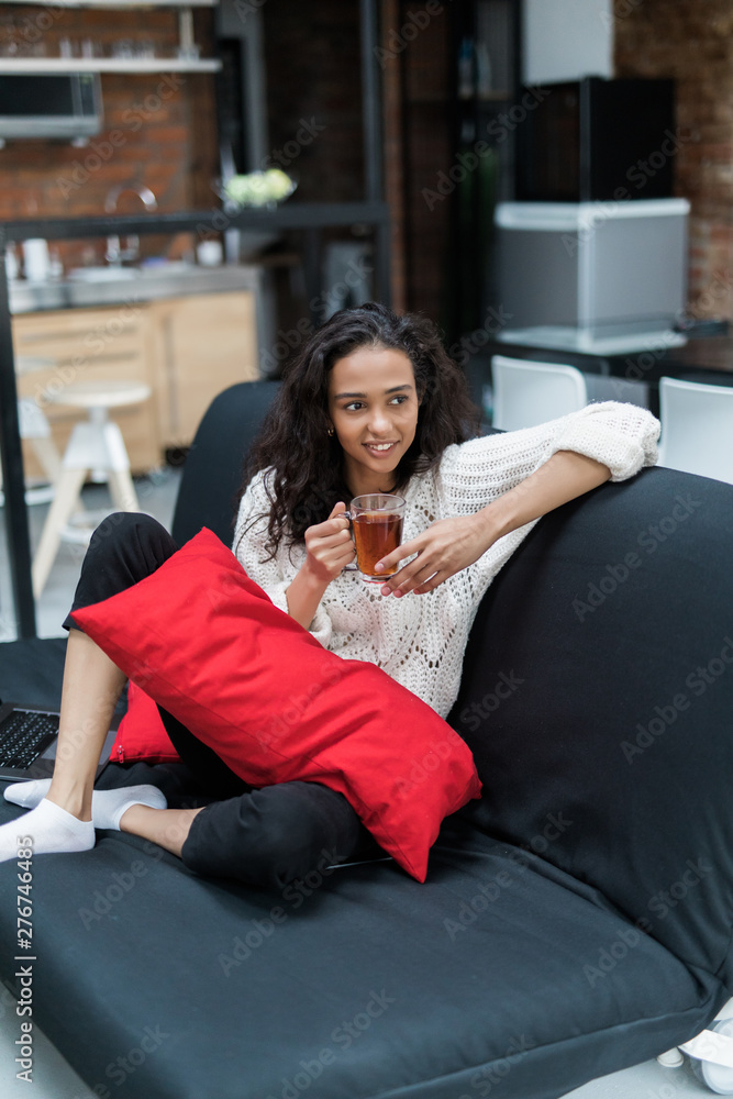 Young woman sitting on couch at home and drinking tea Young woman sitting on couch at home and drinking tea
