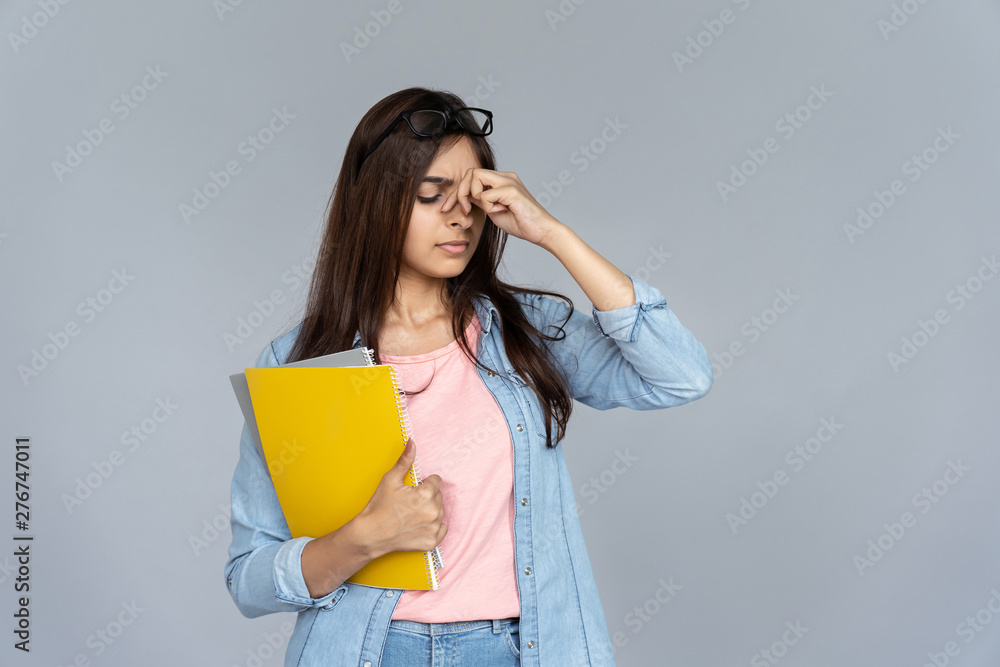 Tired stressed indian young woman student feel hurt eye strain headache from glasses isolated on grey studio background, copy space, dry eyes fatigue, bad eyesight vision problem tension concept Tired stressed indian young woman student feel hurt eye strain headache from glasses isolated on grey studio background, copy space, dry eyes fatigue, bad eyesight vision problem tension concept