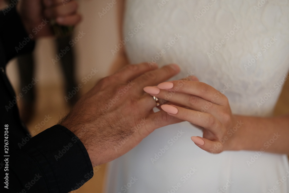 female hand in bridal dress puts a ring on a man's hand female hand in bridal dress puts a ring on a man's hand