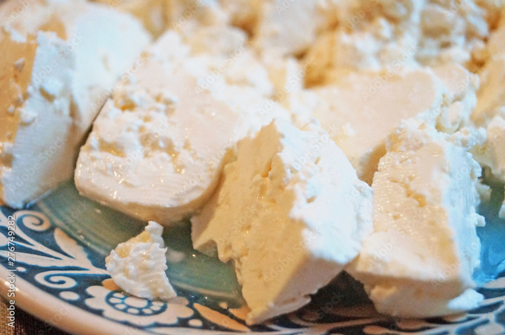 Sliced home-made sheep's cheese on a decorative blue plate with a beautiful pattern on the festive table