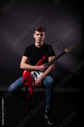 Young caucasian adult posing in the studio with rock guitar