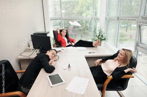 Billede på lærred Three beautiful young girls in business suits are sitting at the office desk