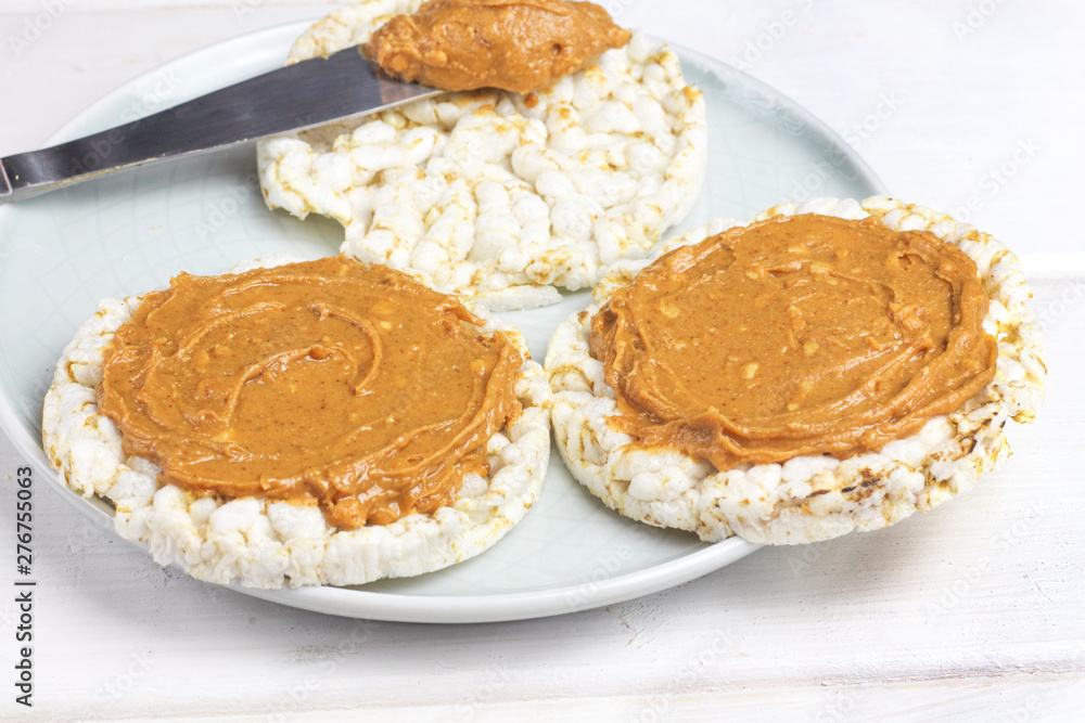 crunchy natural peanut butter sandwich with rice cake bread and knife with peanut butter on plate. Proper nutrition diet vegetarian breakfast crunchy natural peanut butter sandwich with rice cake bread and knife with peanut butter on plate. Proper nutrition diet vegetarian breakfast