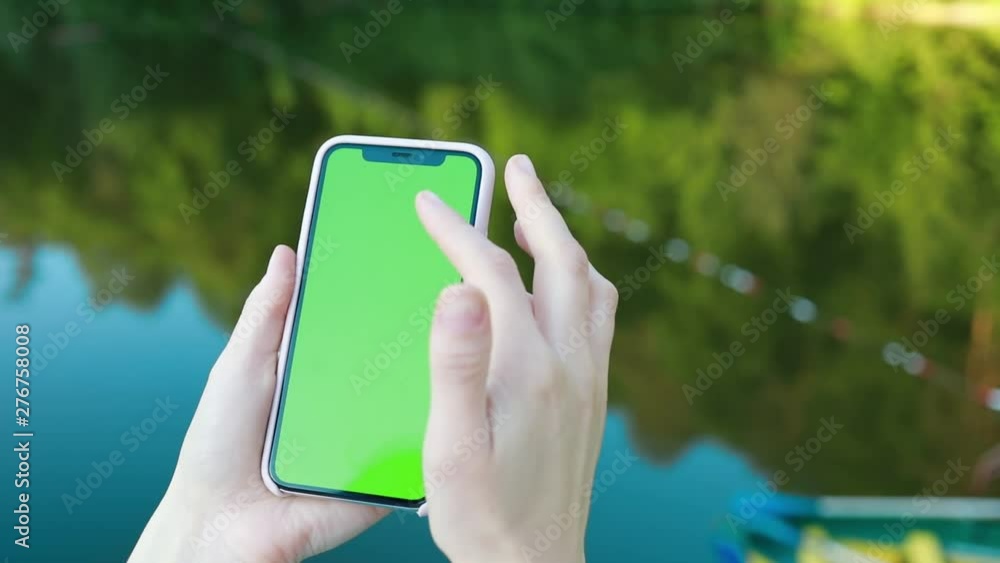 Close up female hands use smartphone scrolling up on lake chroma key green screen Close up female hands use smartphone scrolling up on lake chroma key green screen