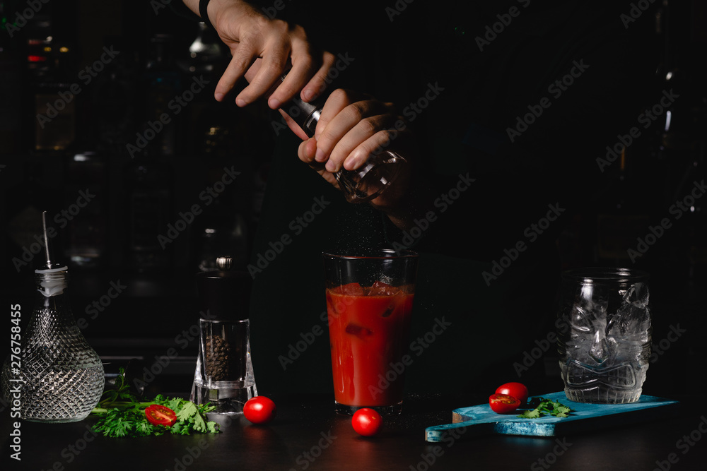Bartender add salt and paper in Bloody Mary Caocktails, making a cocktail, maked with tomato Juice and vodka