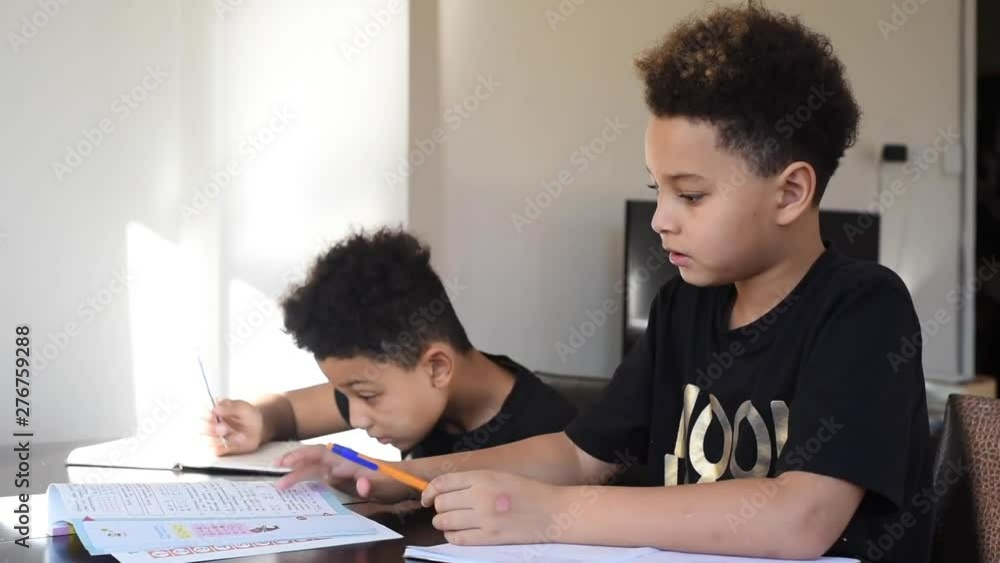 Two cute and handsome mixed brothers doing a homework at home. Two cute and handsome mixed brothers doing a homework at home.
