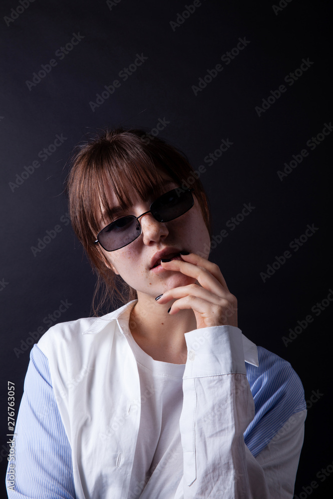 Caucasian Girl in white shirt with black sunglasses posing in the studio Caucasian Girl in white shirt with black sunglasses posing in the studio