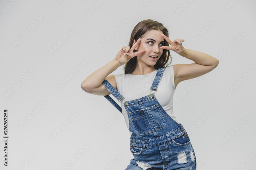Horizontal portrait of pretty woman with puzled expression, finds solution, wears casual t shirt with denim overalls, isolated over white background. Horizontal portrait of pretty woman with puzled expression, finds solution, wears casual t shirt with denim overalls, isolated over white background.
