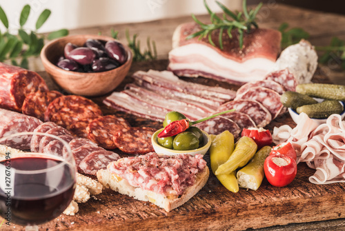 Variety of appetizer on wooden board, wine snack set with prosciutto, salami, ham, olives.