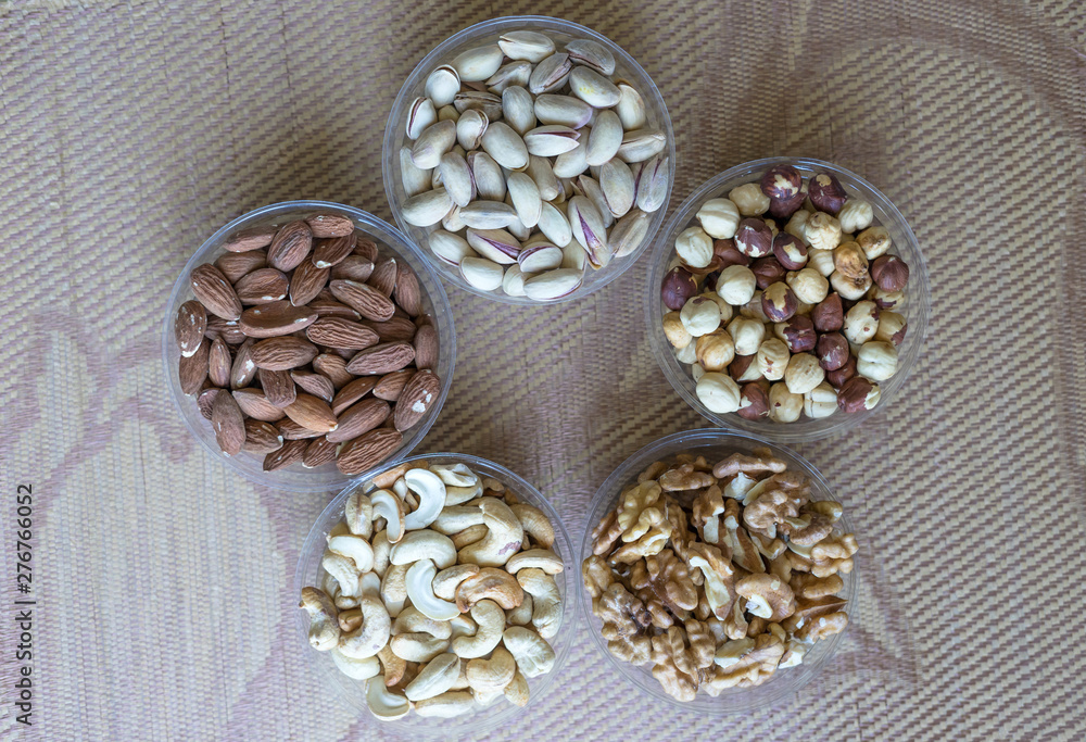 Fototapeta premium Healthy food. Nuts mix assortment on stone texture top view. Collection of different legumes for background image close up nuts, pistachios, almond, cashew nuts, peanut, walnut. image