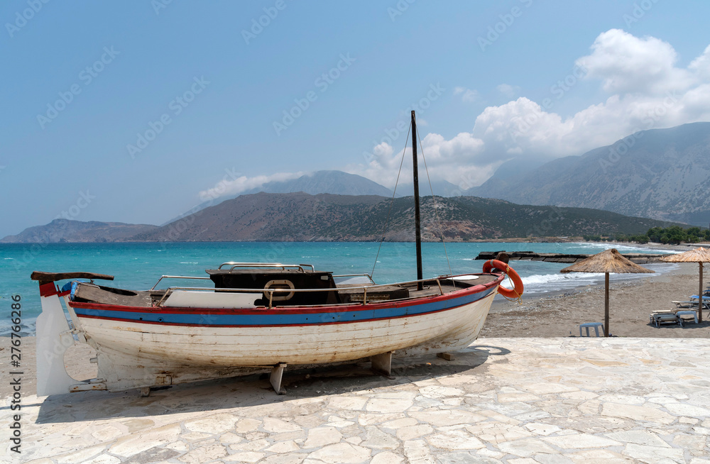 Crete, Greece. June 2019. A small boat painted red white blue with a background of the coast and mountains
