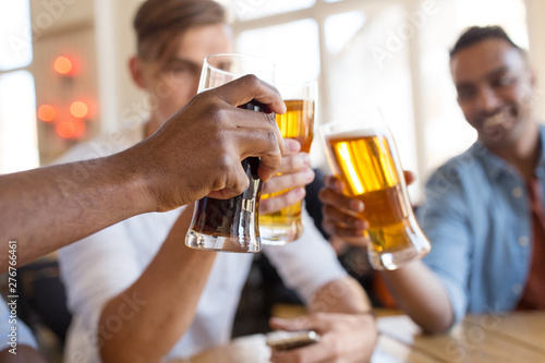 drinks, leisure and celebration concept - happy male friends drinking beer and clinking glasses at bar or pub