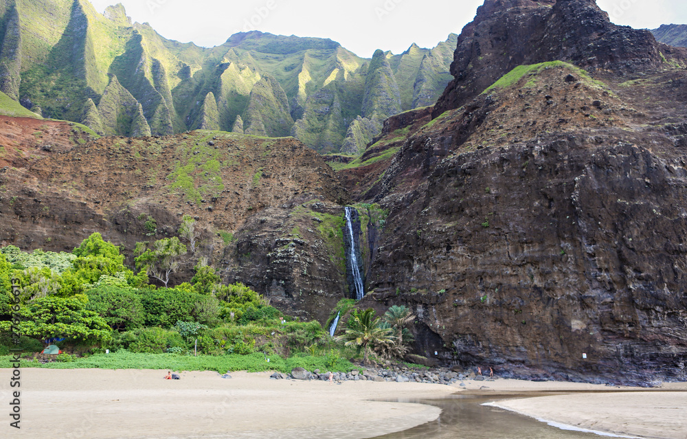 Φωτογραφία Waterfall coming off the cliff onto the beach at Kalalau on the Napali Coast, the northern shore of Kauai