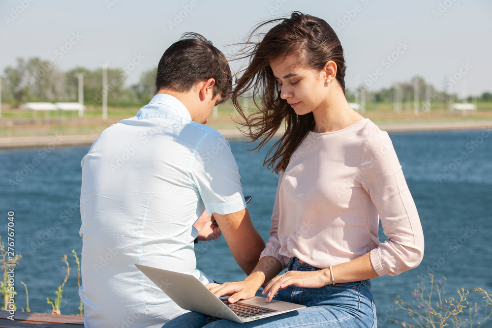 Obraz premium Man and woman using laptop outdoors. Image of young couple man and woman in casual clothes.