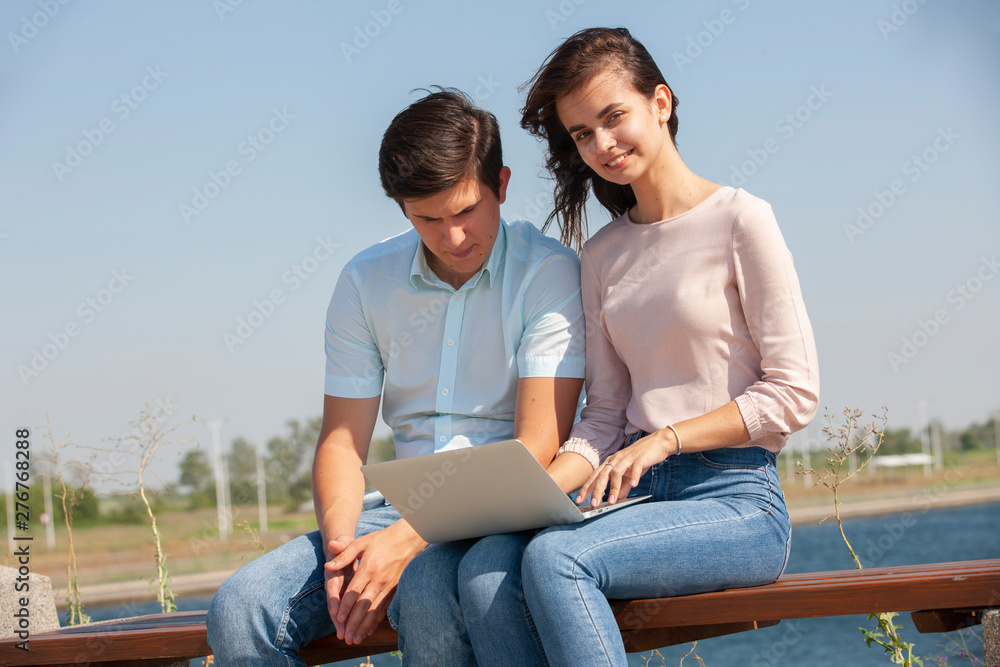 Couple using a laptop outdoors and looking happy