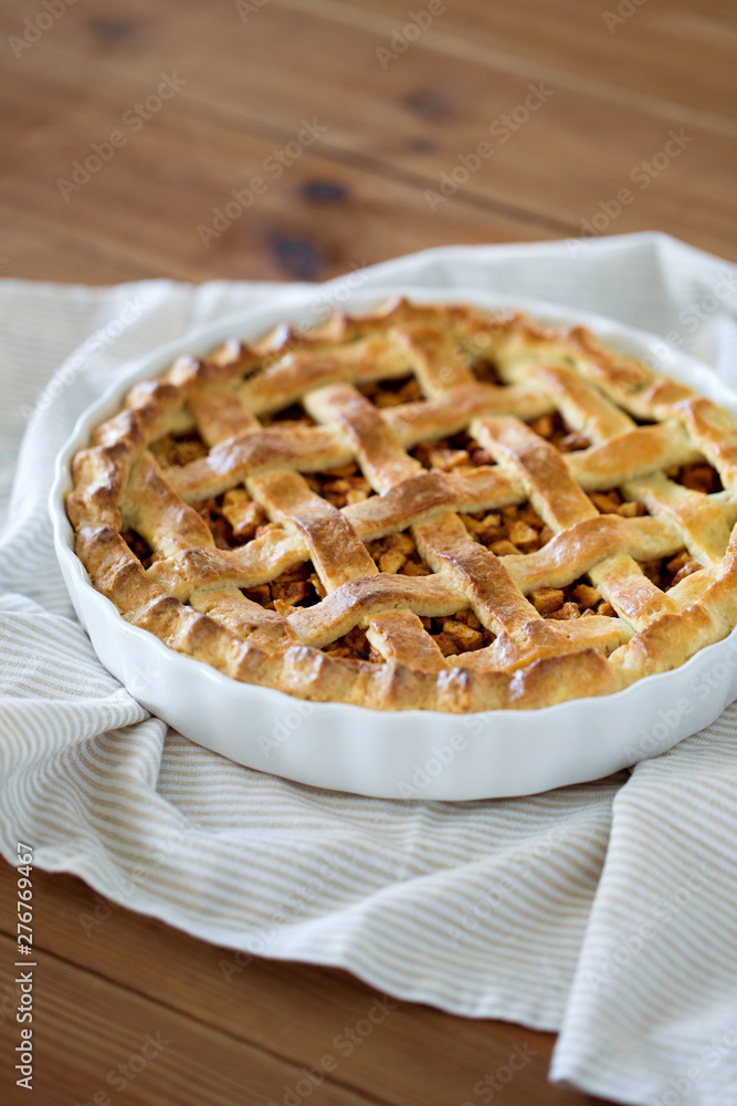food, culinary and cooking concept - close up of apple pie in baking mold with kithchen towel on wooden table food, culinary and cooking concept - close up of apple pie in baking mold with kithchen towel on wooden table