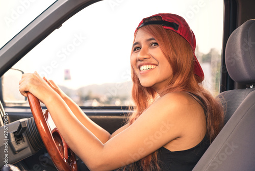 Asian trendy cool woman driving car with bright sun - Happy ethnic diverse Thai girl inside vehicle travelling on fun summer road trip - Holiday, vacation & millennial generation activity - face focus