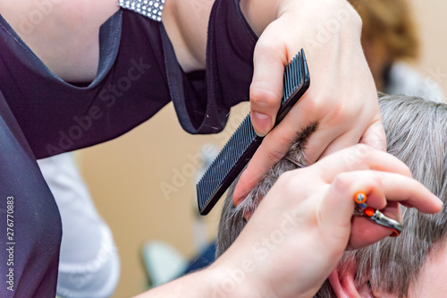 hairdresser working with scissors, white-haired woman