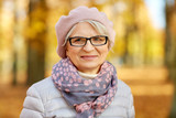 old age, retirement and season concept - portrait of happy senior woman in glasses at autumn park