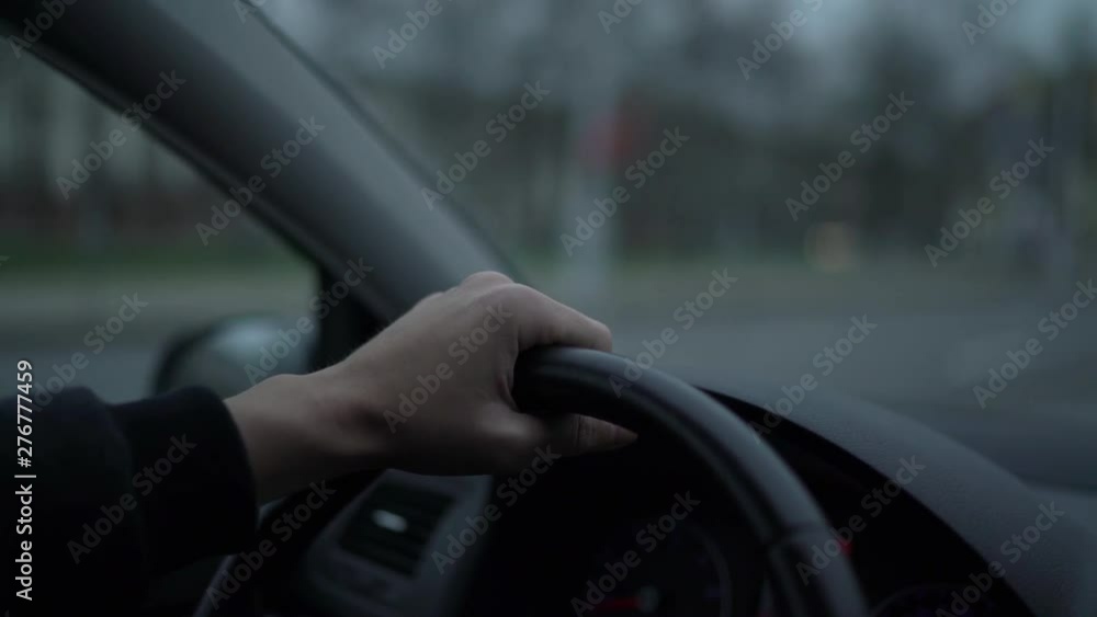 Man is traveling by car in the evening, hand on a steering wheel. Close up Man is traveling by car in the evening, hand on a steering wheel. Close up