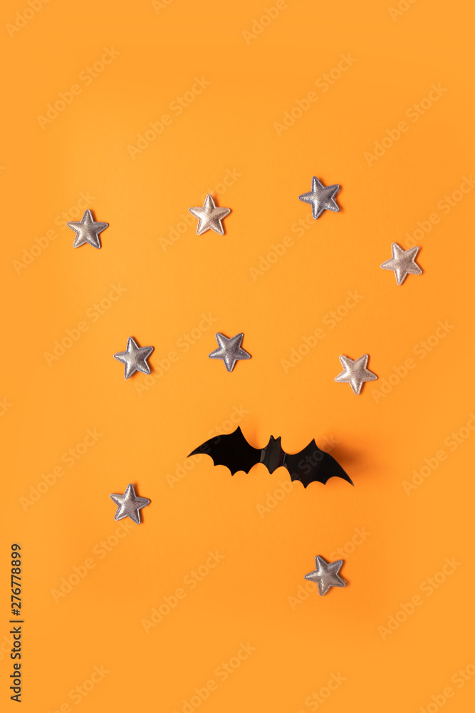 Halloween holiday concept of black paper bats fly up and gold stars on an orange background, top view. Halloween holiday concept of black paper bats fly up and gold stars on an orange background, top view.