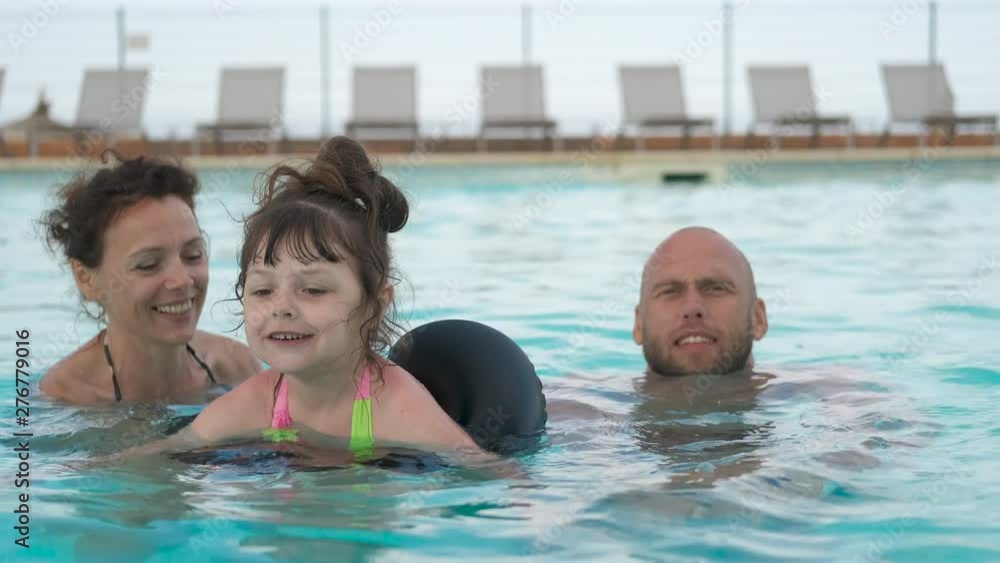 Happy family in the pool. Parents with their daughter swim in the pool at the resort. Happy family in the pool. Parents with their daughter swim in the pool at the resort.