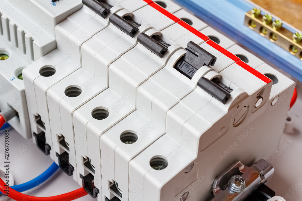 Installed automatic circuit breakers on DIN rail in white plastic mounting box closeup Installed automatic circuit breakers on DIN rail in white plastic mounting box closeup