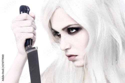 Beautiful and scaring witch woman in white with a knife and meat. Concept image for Halloween