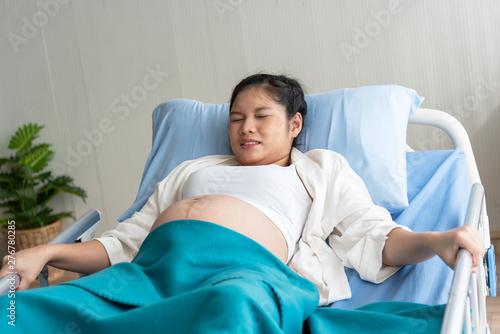 The pregnant woman is suffering Because close to the birth, lying in a patient bed And bring to the deliver room, to maternity and health concept.