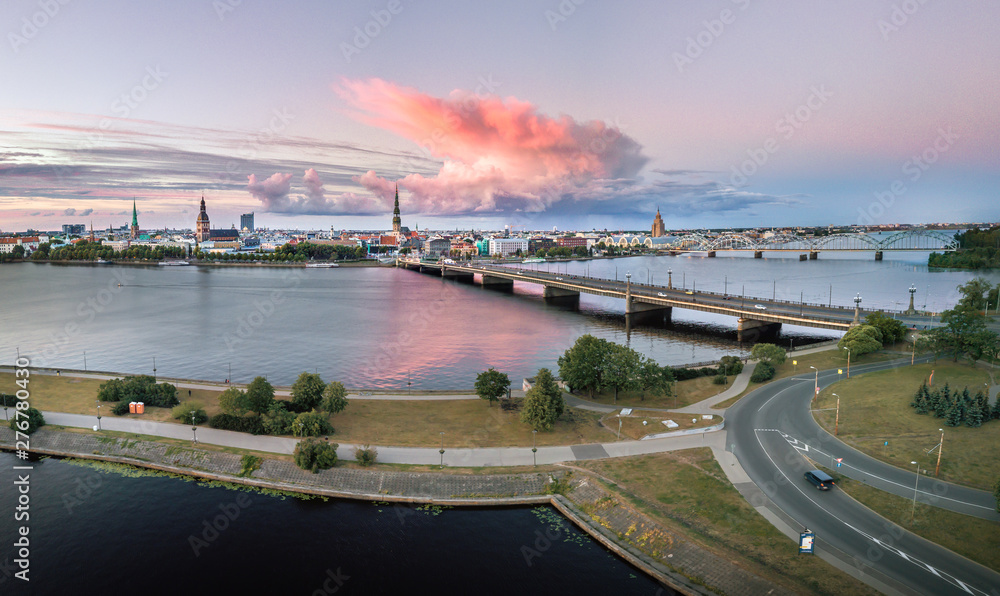 Panoramic, aerial view over Riga city covered in colorful storm clouds along the river. Iconic old town panorama in vivid sunset colors. Picturesque scenery of historical architecture. 