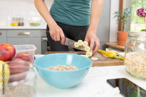 Woman preparing healthy fitness breakfast  oatmeal with bananas  strawberries and chia seeds