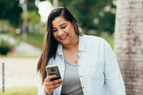 Portrait of beautiful plus size woman using her smartphone outdoors