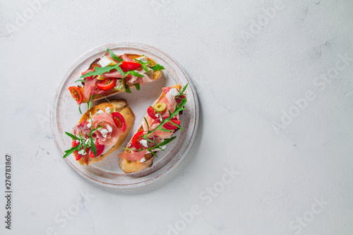 Three bruschetta with jamon and cheese on a white round plank white background. Top view with copy space for your text