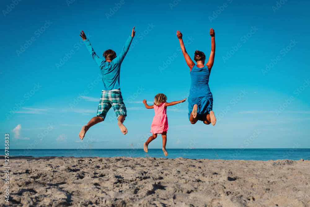 happy family- mom, dad and little daughter- jumping on beach
