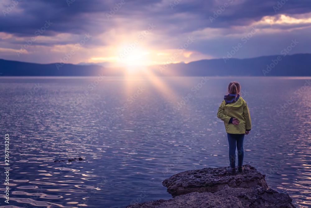 Obraz premium Little girl standing on the lakeshore