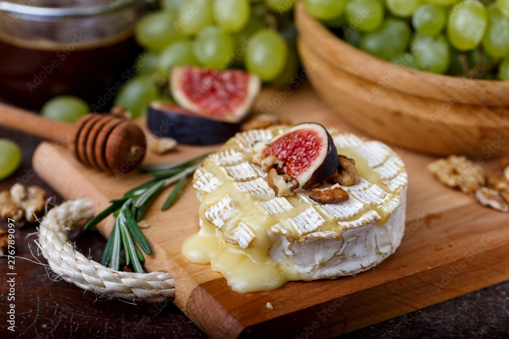 Baked Camembert on wooden board, grapes, figs, nuts, honey, herbs Baked Camembert on wooden board, grapes, figs, nuts, honey, herbs