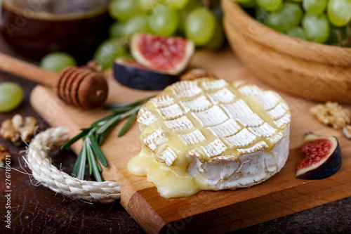 Baked Camembert on wooden board, grapes, honey, nuts