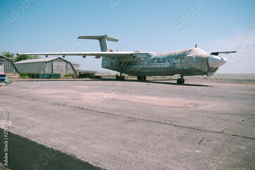 Slika na platnu abandoned military aircraft on an empty airfield near the hangar against the blue sky