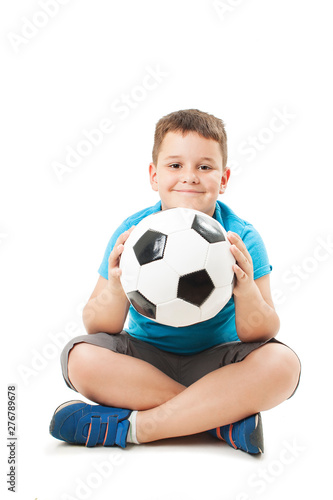 Cute boy is holding a football ball made of genuine leather. Sitting on floor.  Isolated on a white background. Soccer ball © Jelena Ivanovic
