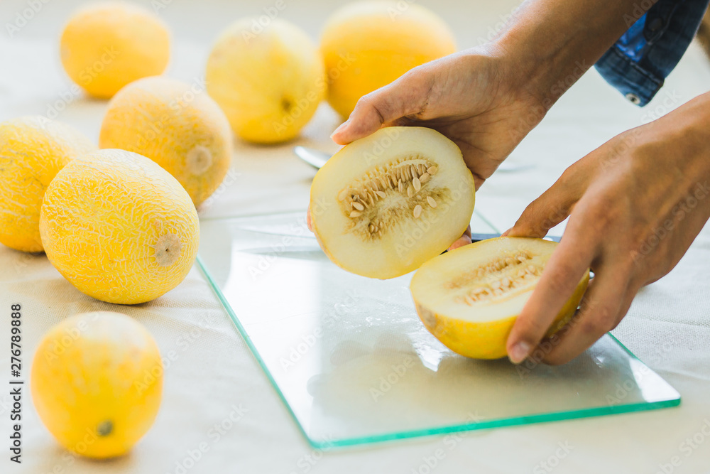 Melon berries on the kitchen table, hands cut melon into halves . Melon berries on the kitchen table, hands cut melon into halves .