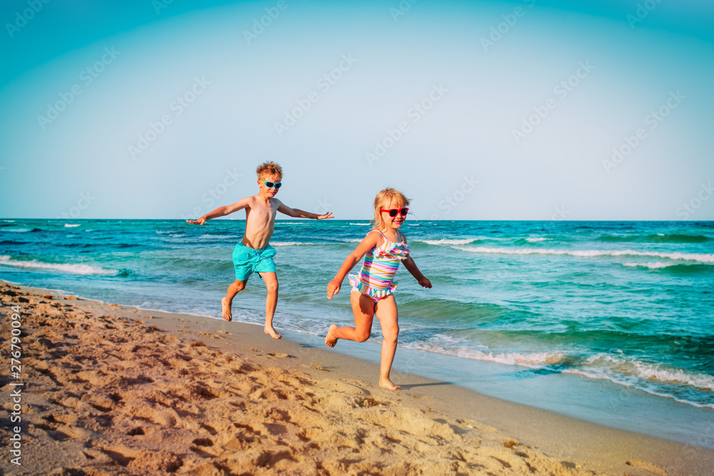 cute happy girl and boy running on beach